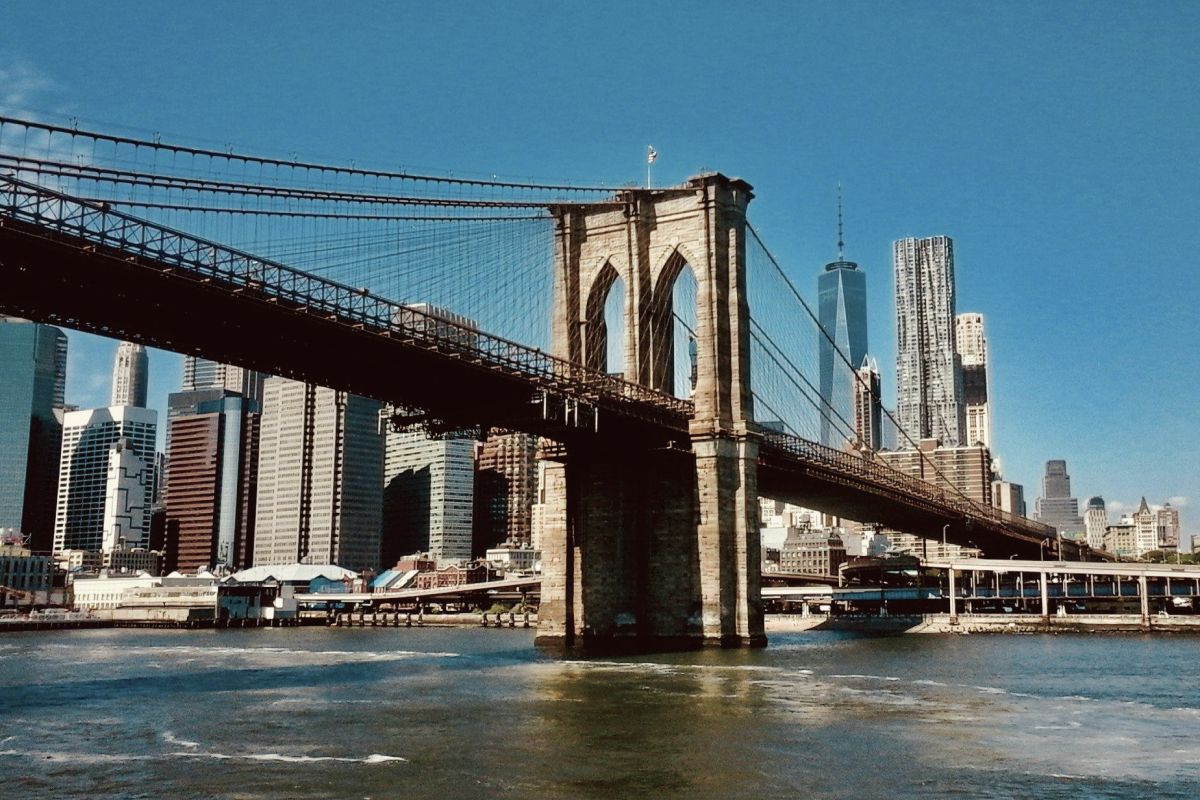 Brooklyn Bridge vom Wasser aus fotografiert, im Hintergrund sieht man Manhattan