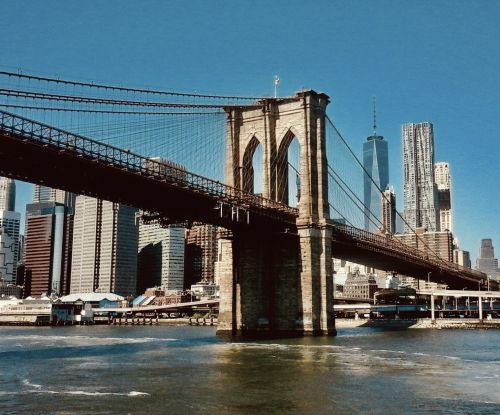 Brooklyn Bridge vom Wasser aus fotografiert, im Hintergrund sieht man Manhattan