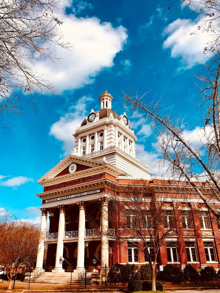 Braun-weißes Gebäude aus der Kolonialzeit mit Turm auf dem Uhren angebracht sind