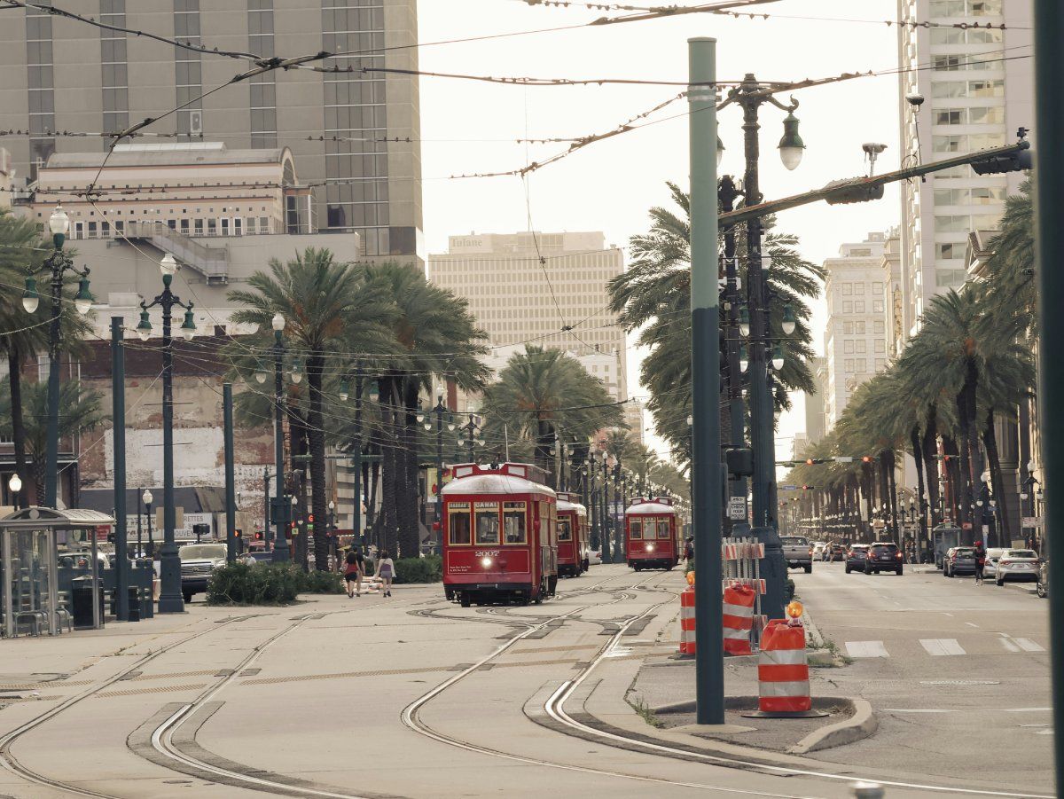 Canal Street in New Orleans, auf der linken Straßenseite fahren drei altertümliche rote Trams